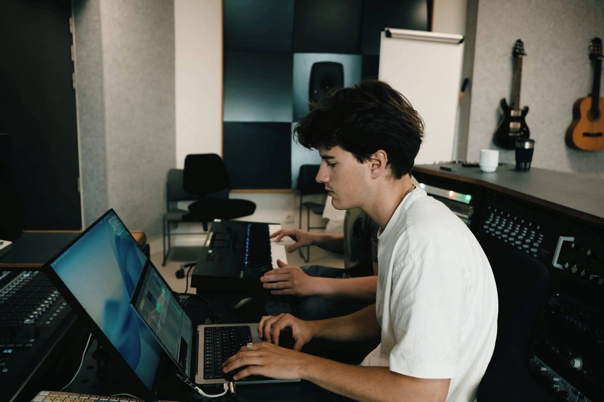 Person ved computeren og mixerpulten i et studie